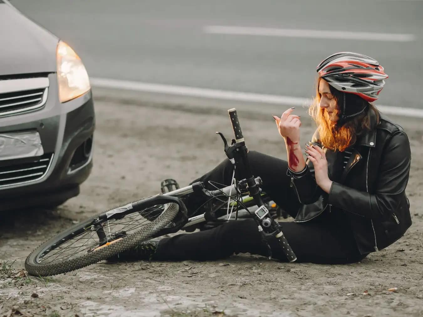 Cyclist sitting on the ground next to a damaged bicycle after a road accident