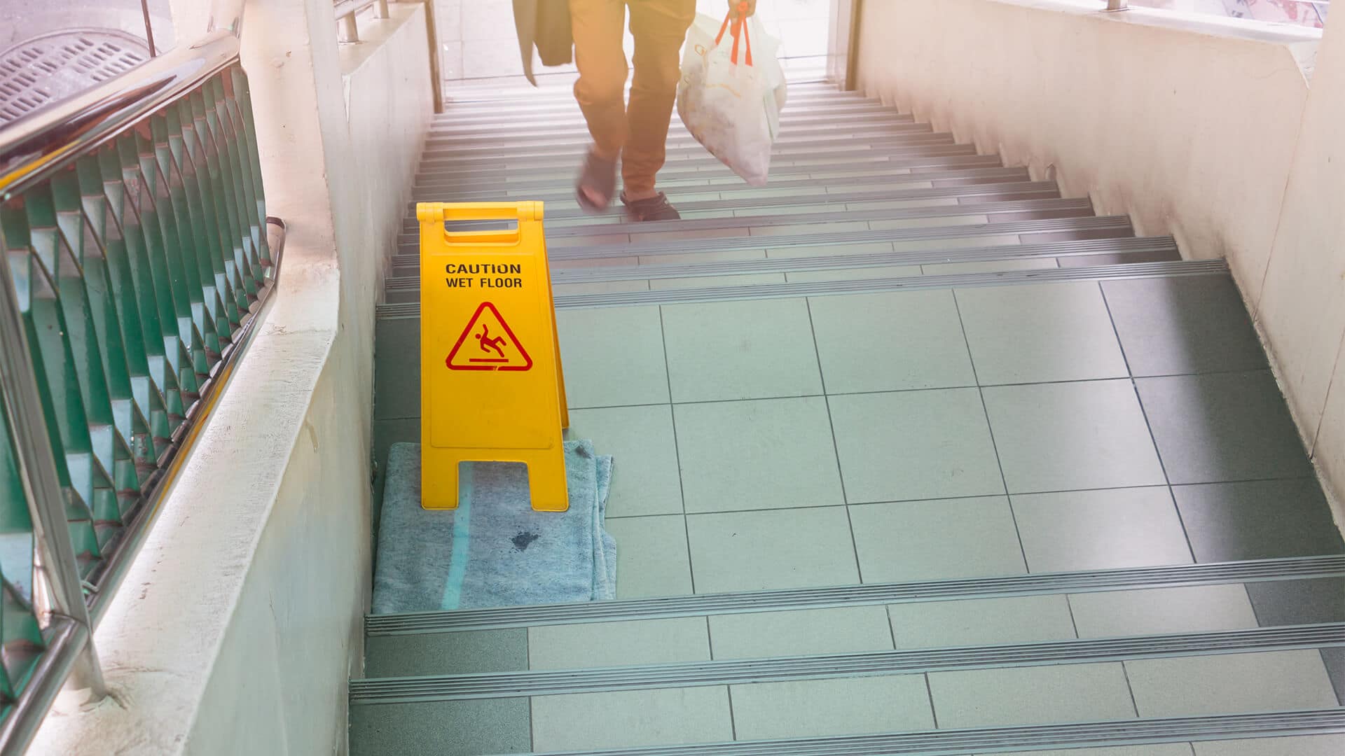 Wet floor caution sign at the bottom of a staircase