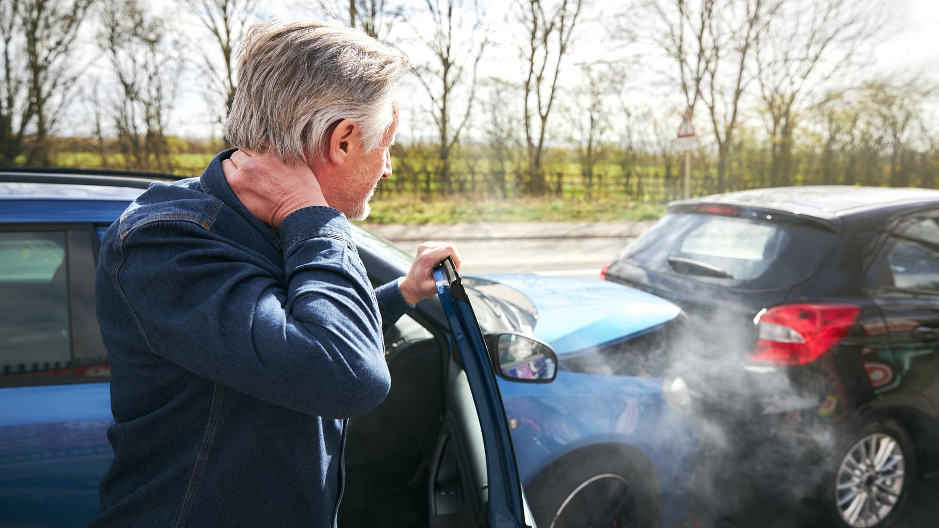 man looking at the car after a car accident