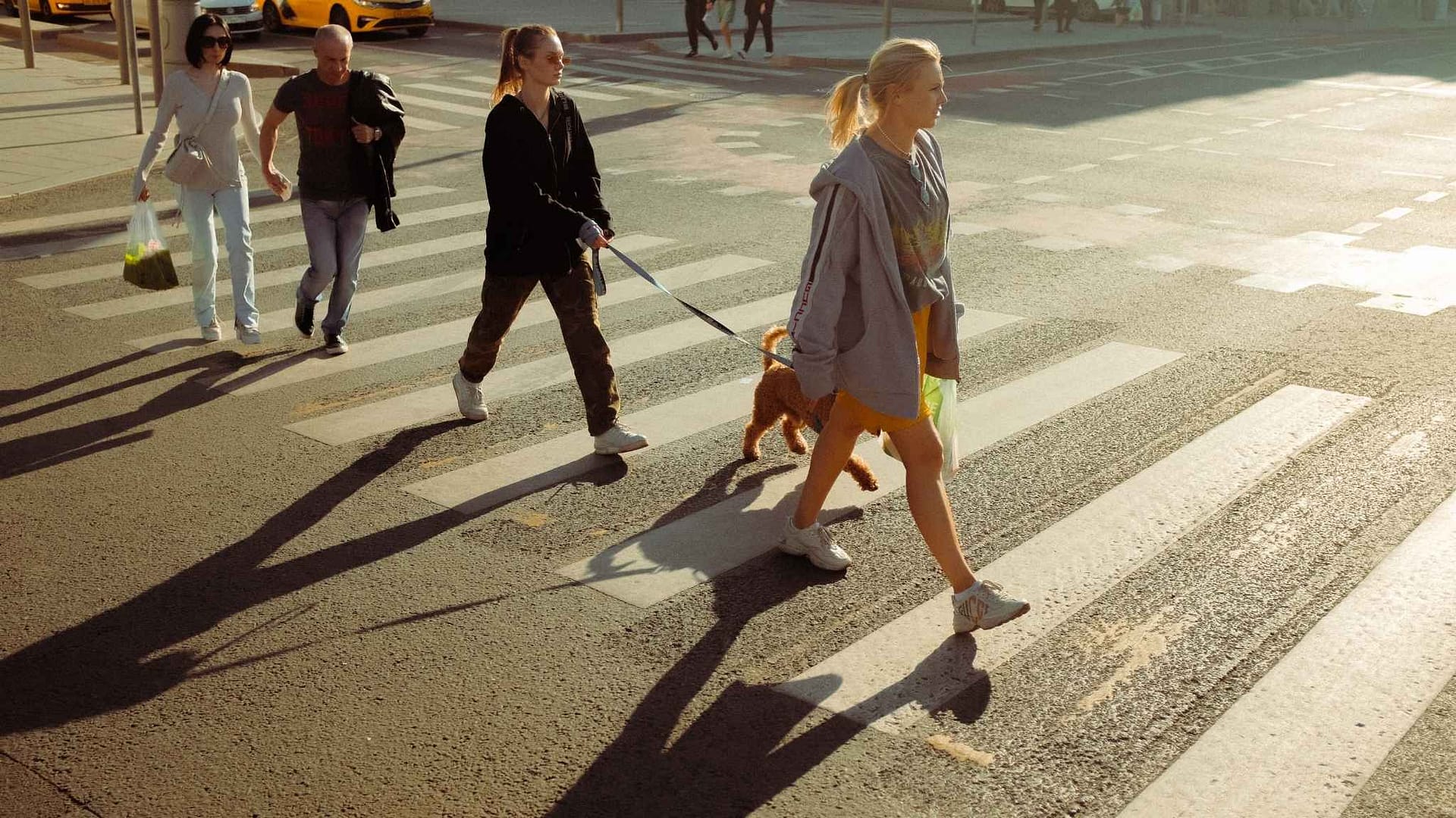 Group of pedestrians crossing a marked crosswalk in an urban intersection.