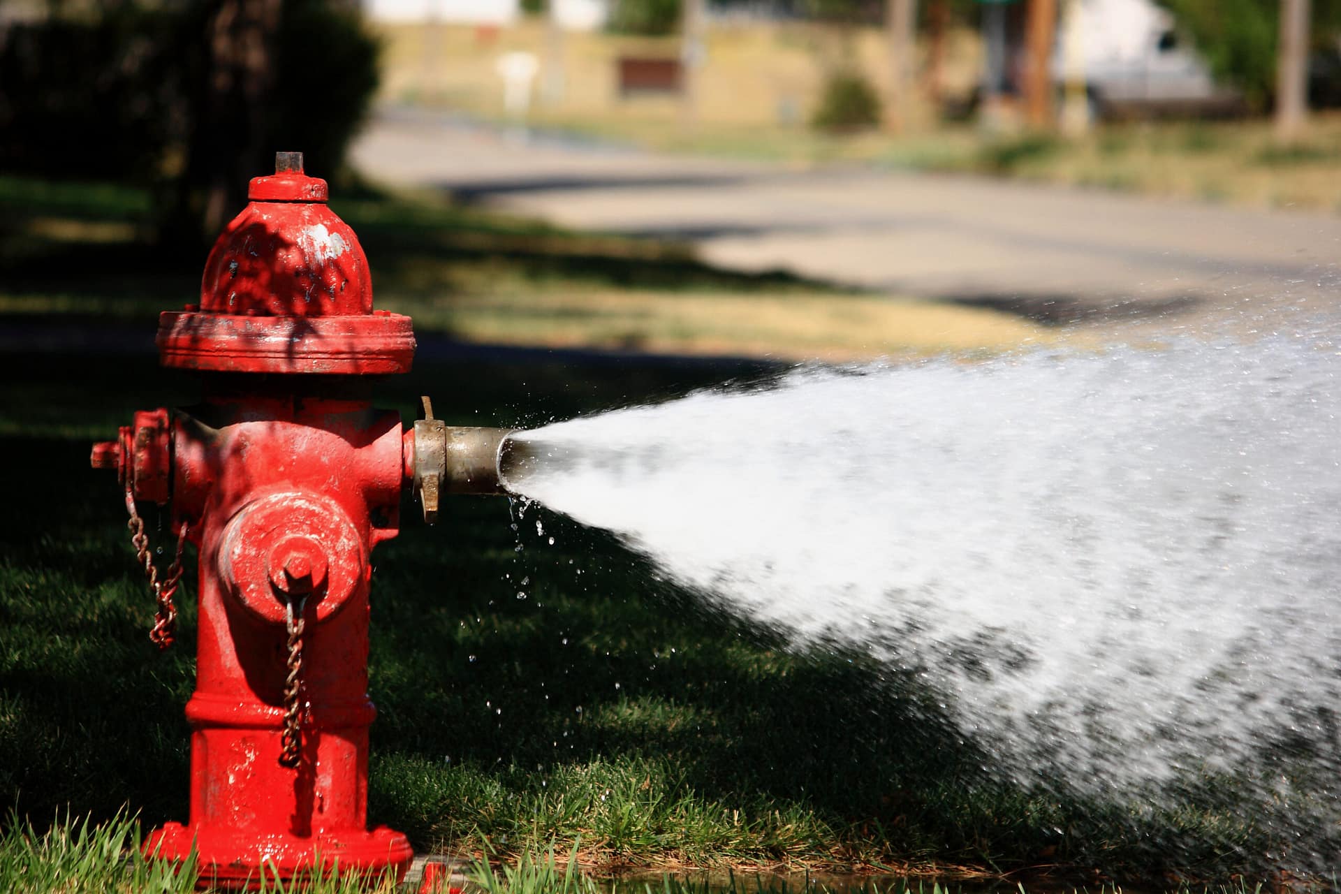 Red fire hydrant spraying water at high pressure outdoors