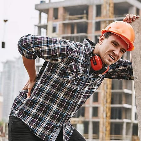 Dallas Crane Accident Lawyer: Causes, Liability, Common Injuries, and Your Legal Rights 4 Construction worker holding their lower back at an active building construction site.
