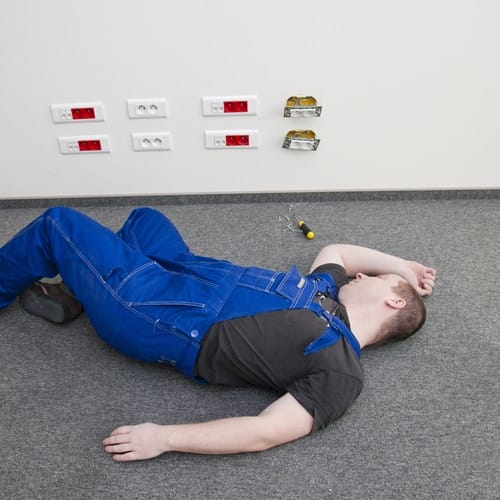 Worker lying on the floor after an electric shock accident near an electrical panel