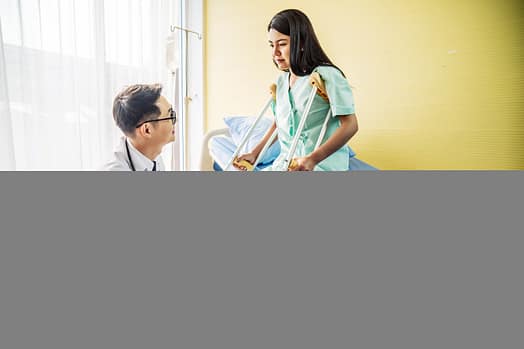 Médico o fisioterapeuta asiático que examina la rodilla de una paciente con una pierna o rodilla lesionada después de un accidente automovilístico y le explica el diagnóstico del problema en la clínica.