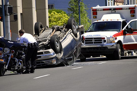 Car rolled over with ambulance in the background