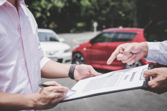 Two people reviewing and signing documents outdoors after an incident