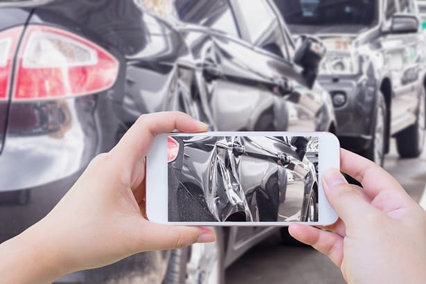 Mano que usa un teléfono inteligente para tomar fotografías de los daños causados ​​por un accidente de tráfico para el seguro. Abogado de lesiones personales. Comparativo. Seguros GEICO.