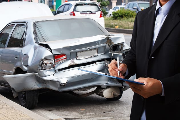 Agentes de seguros de automóviles escriben en portapapeles información sobre daños en accidentes automovilísticos.