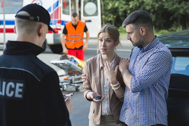 Two people speaking with a police officer outdoors
