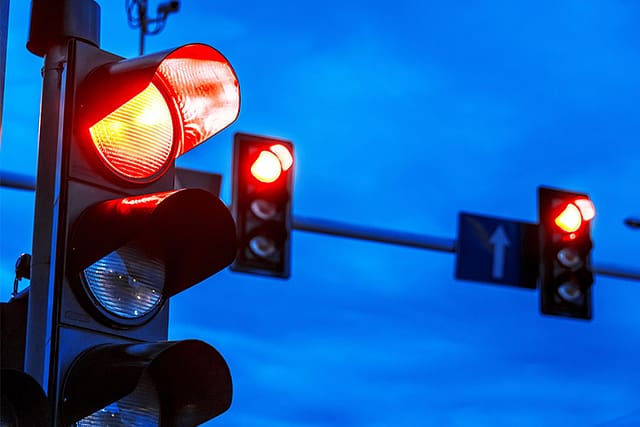 Traffic lights showing red signals at an urban intersection at night.