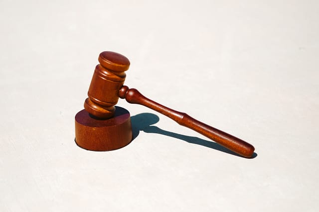 Wooden gavel resting on its sound block against a white background.