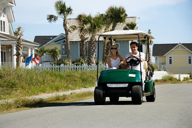 Caucasian mid-adult man and woman driving golf cart down residential street. Texas golf cart accident lawyers