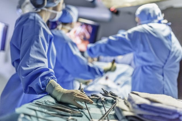 Surgical team operating on a patient with medical instruments visible in the foreground