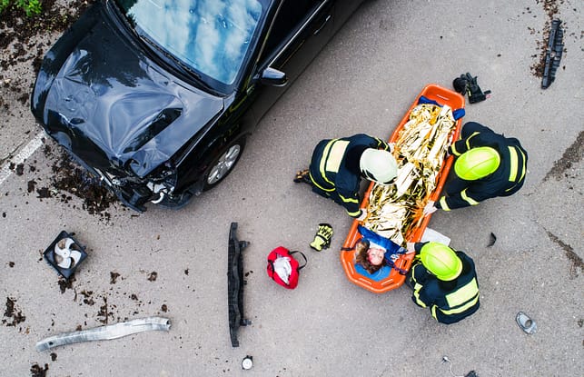 A young injured woman in a plastic stretcher after a car accident, covered by thermal blanket. Top view. Schertz Car Accident Lawyers