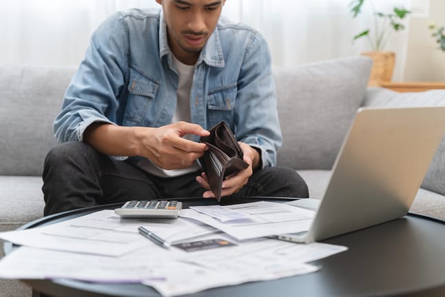 Young man opening empty wallet stress to find money to pay debts. What Judgment Proof Means