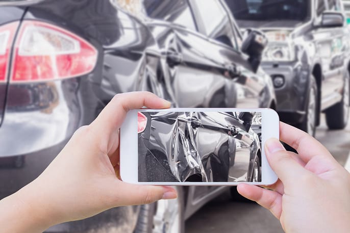 Mano usando un teléfono móvil inteligente tomando fotos de los daños del accidente automovilístico para el seguro. Abogado de lesiones personales. Leyes de negligencia comparada de Texas