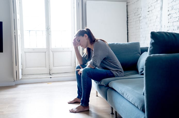 Joven y atractiva mujer latina tumbada en el sofá de la sala de casa sintiéndose triste, cansada y preocupada por sufrir depresión en la salud mental, problemas y concepto de corazón roto. Costo emocional de lesiones personales