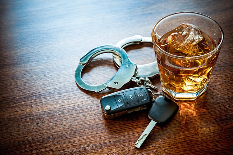 Car keys handcuffs and a glass of alcohol on a table representing drunk driving consequences