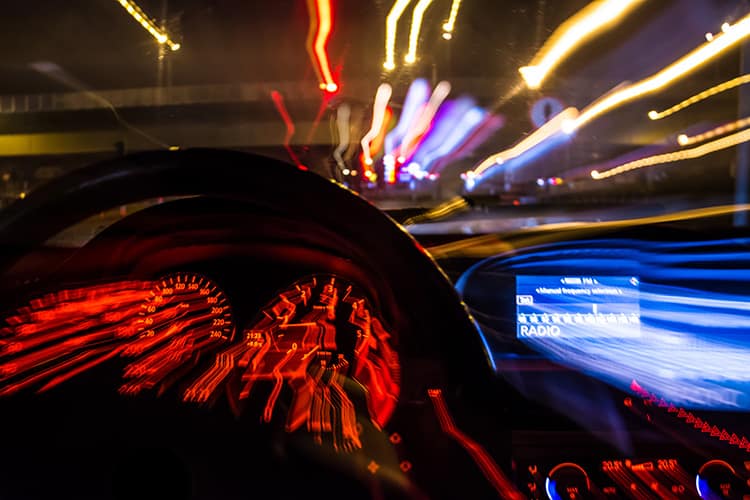 Blurred view from inside a car dashboard at night suggesting high speed or impaired driving